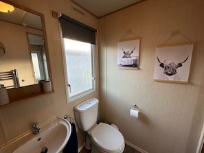 Ein Badezimmer mit Toilette, Waschbecken und Spiegel. An der Wand hängen zwei Bilder in Rahmen.