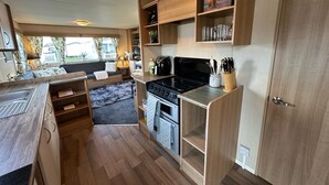 A compact kitchen with a stove, oven, and wooden cabinets. - A Beautiful, Dog Friendly Holiday Home (Mablethorpe)