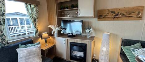 A cozy living area with a sofa, a small table with a lamp, a television, and a decorative wall piece.