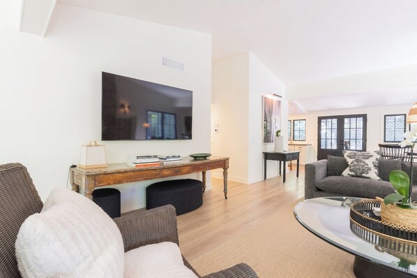Ein modernes Wohnzimmer mit einem Flachbildfernseher, einem Holztisch und einem grauen Sofa.