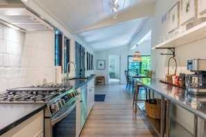 A modern kitchen with a central island, stainless steel appliances, and a view into the dining area. - Secluded 3-Bedroom Luxury Retreat near Beach – Perfect Getaway! (Douglas)