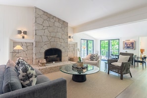 A living room with a stone fireplace, a glass coffee table, and a comfortable seating area. - Secluded 3-Bedroom Luxury Retreat near Beach – Perfect Getaway! (Douglas)