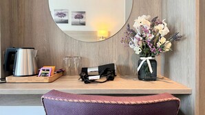A wooden desk with a mirror, a vase of flowers, a kettle, and a tray with a box and glasses. - Fyne Rooms - Bute Superior King - Bed & Breakfast (Tighnabruaich)