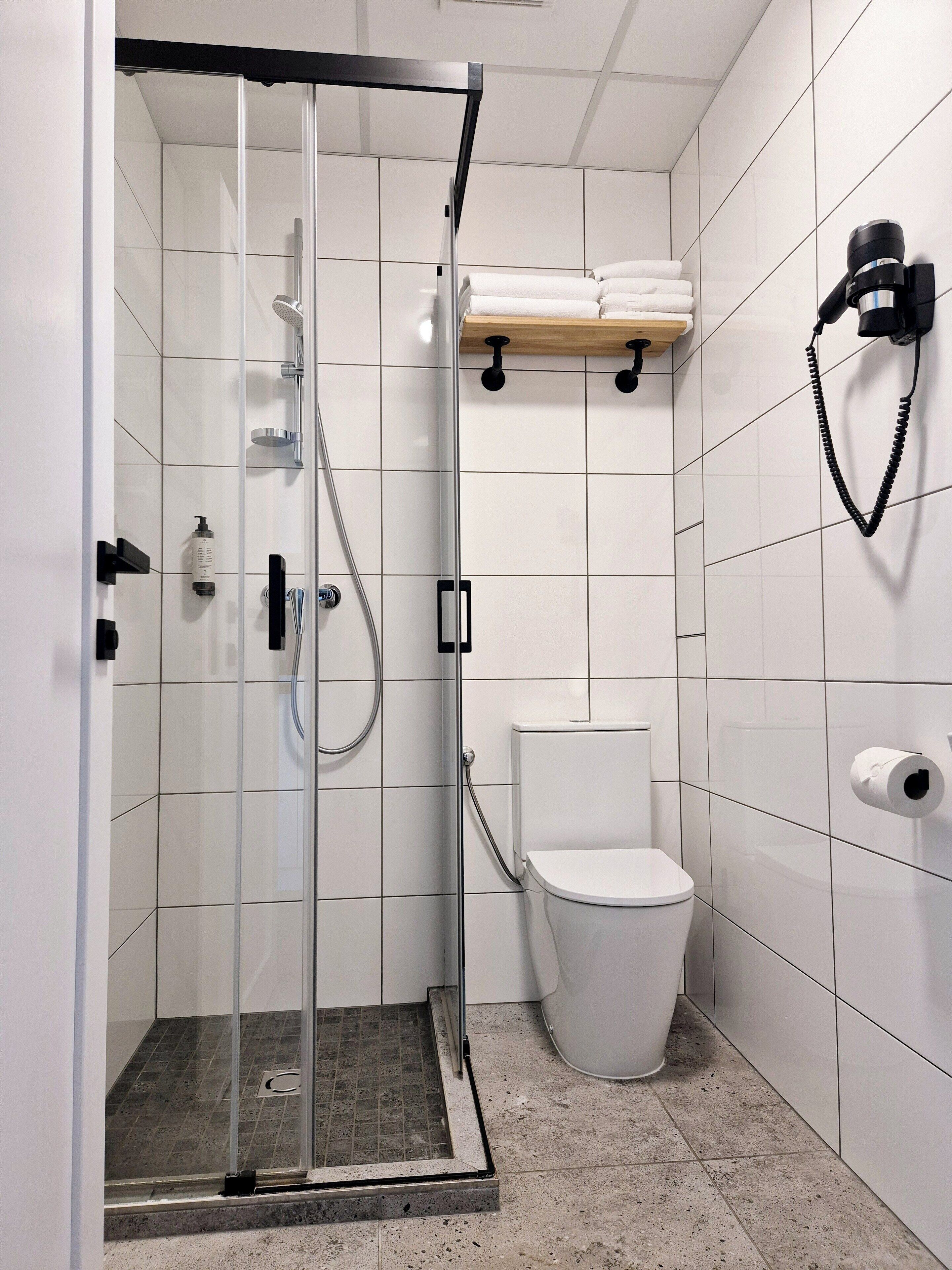 A modern bathroom with a glass-enclosed shower, a toilet, and a towel rack.