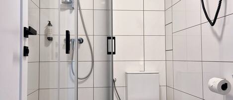 A modern bathroom with a glass-enclosed shower, a toilet, and a towel rack.