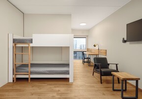 Una habitación moderna y minimalista con una cama litera, un escritorio, una silla y una pequeña mesa.
