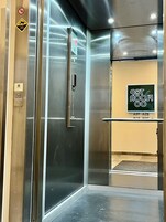 Interno di un ascensore con pareti metalliche, una ringhiera e un cartello che indica il numero del piano.