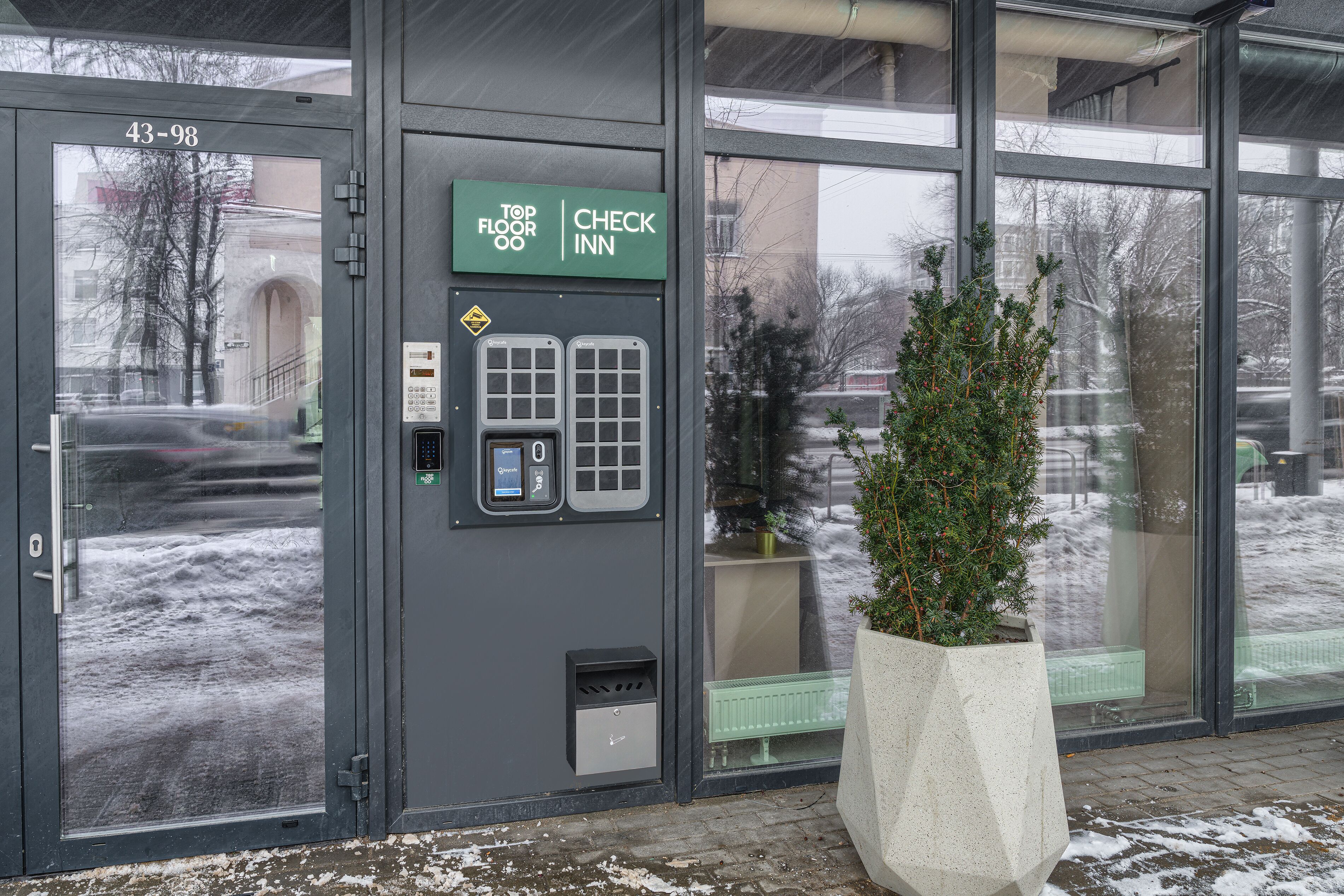 A hotel entrance with a 'Top Floor' sign, a 'Check In' sign, and a digital keypad for room access.