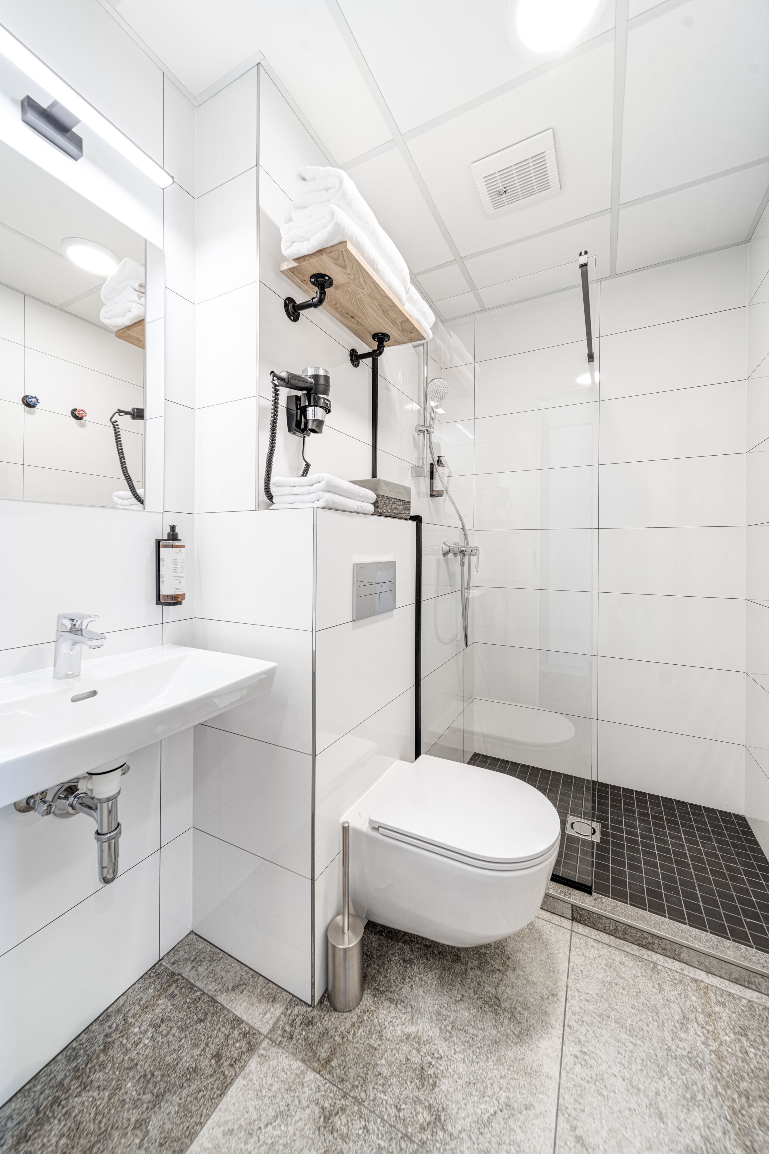 Ein modernes Badezimmer mit einem weißen Waschbecken, einer Toilette und einer Dusche.
