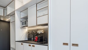 A modern kitchen with white cabinets, a black countertop, and a microwave.