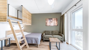 A modern room with a bunk bed, a sofa, a small table, and a large window offering a city view.