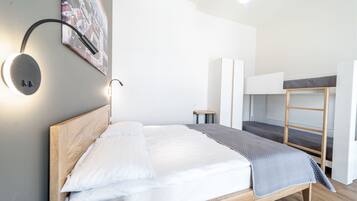 Una habitación de hotel moderna con una cama de madera, una cama literera, una lámpara de pared redonda y una pintura de un paisaje urbano.