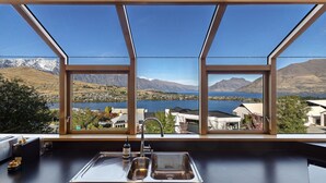 A kitchen with a large window overlooking a lake and mountains. - Picturesque on Peregrine - close to town with views (Queenstown)