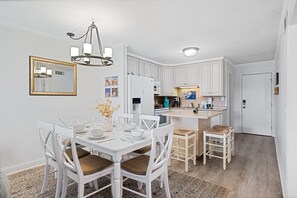 A modern kitchen with white cabinetry, a dining table with chairs, and a chandelier. - Beachfront Resort • King Suite • Super Clean • Many Extras Plus Resort Amenities (Hilton Head Island)