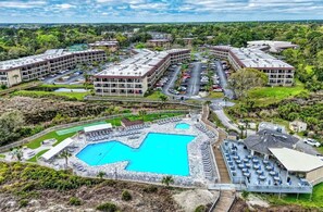 A resort with multiple buildings, a large central pool, and a parking area. - Beachfront Resort • King Suite • Super Clean • Many Extras Plus Resort Amenities (Hilton Head Island)