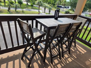 A balcony with a table and two wicker chairs.