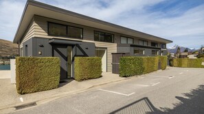 Un edificio moderno con techo plano, ventanas grandes y entrada protegida por una reja.