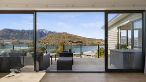 Un interior moderno con un puertas correderas de vidrio que dan a un balcón con vistas a un lago y montañas.