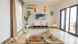 Una sala de estar moderna con un conjunto de sofás, una mesa de centro y un televisor montado en la pared.