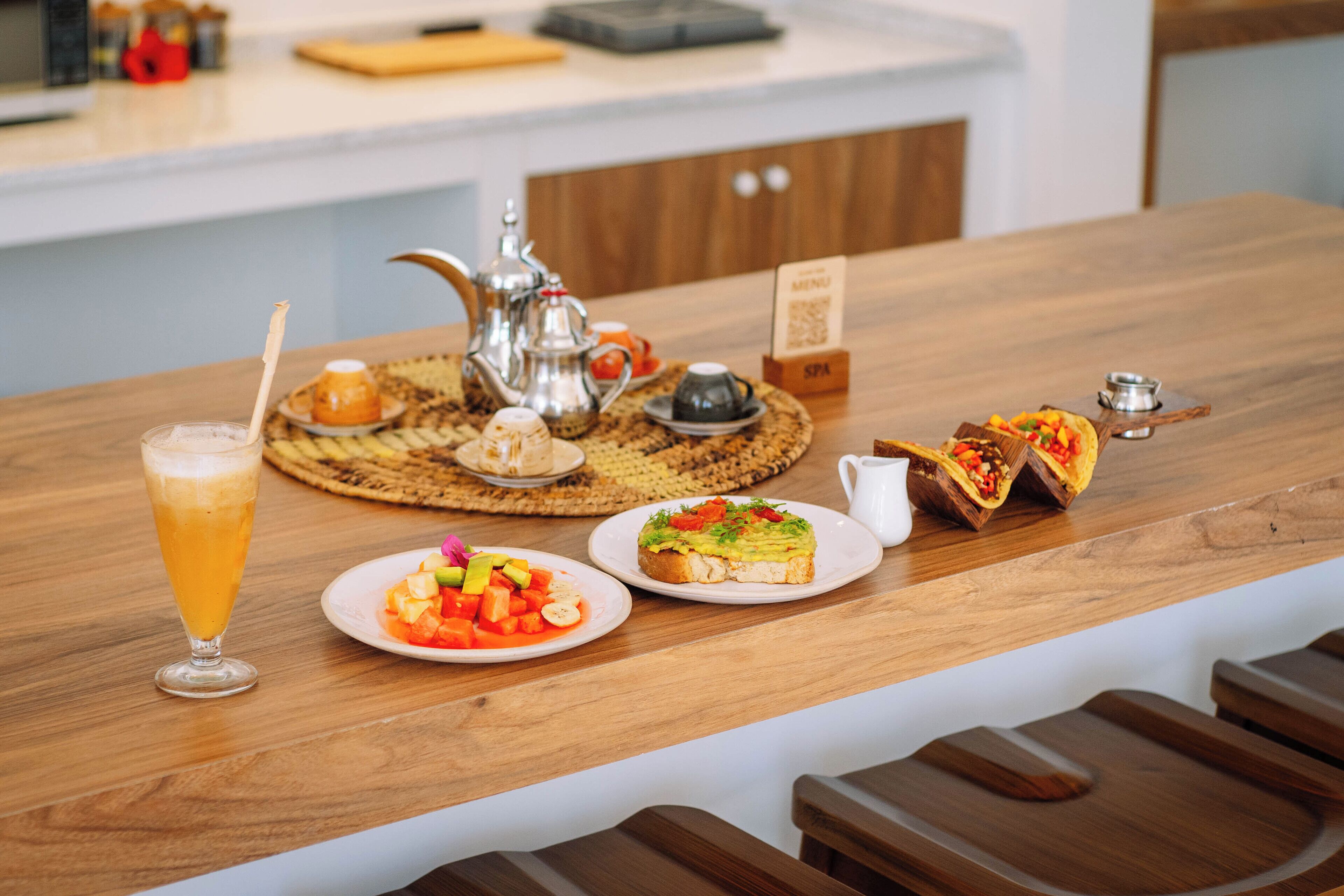 Ein Holztisch mit verschiedenen Speisen, darunter ein Glas Bier, eine Fruchtschale und ein Sandwich.