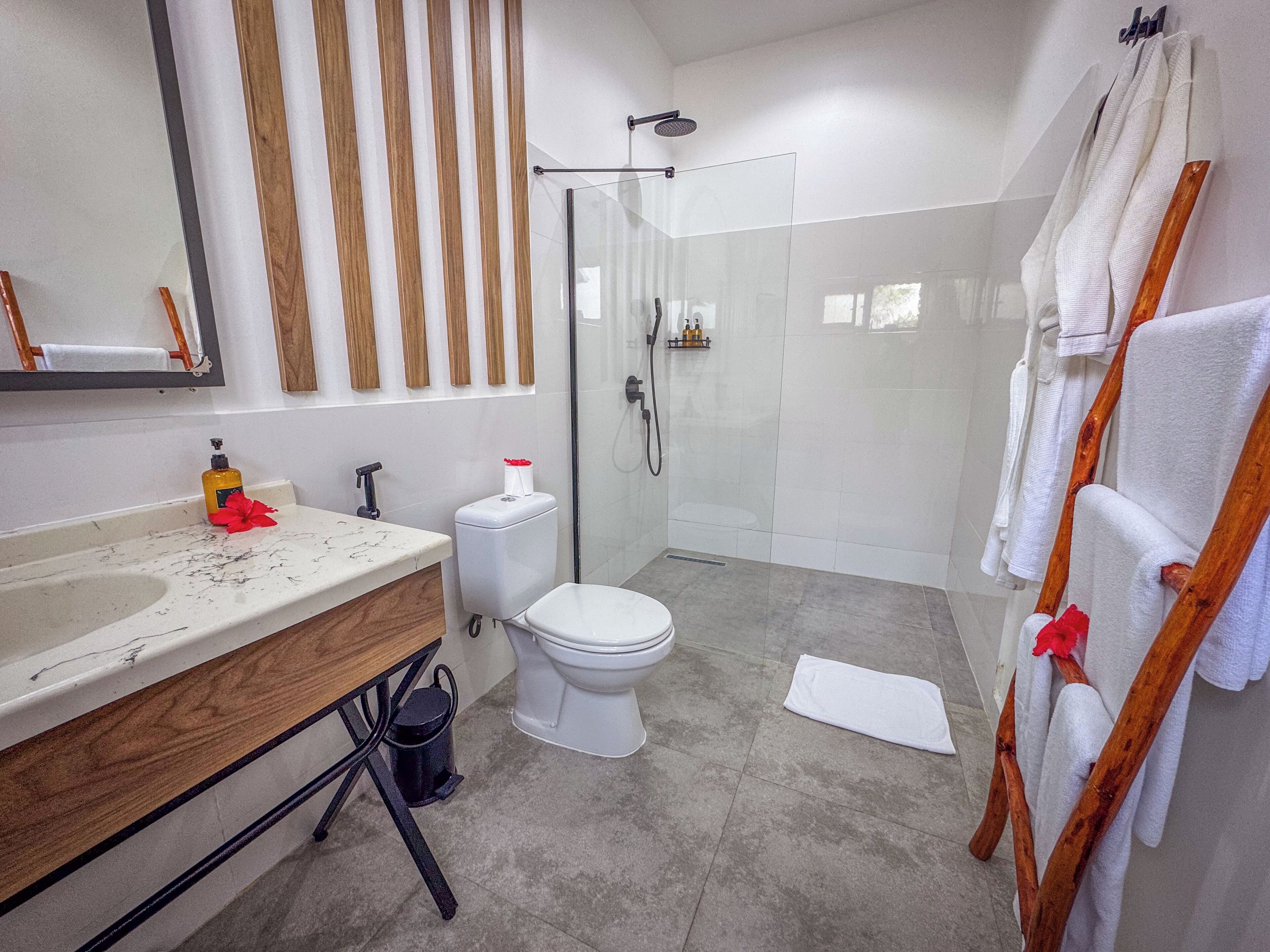Une salle de bain moderne avec une douche en verre, des toilettes et un meuble-lavabo avec un miroir.