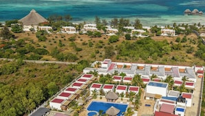 Vista aérea de un complejo turístico con varias edificaciones, una piscina y una zona de playa.