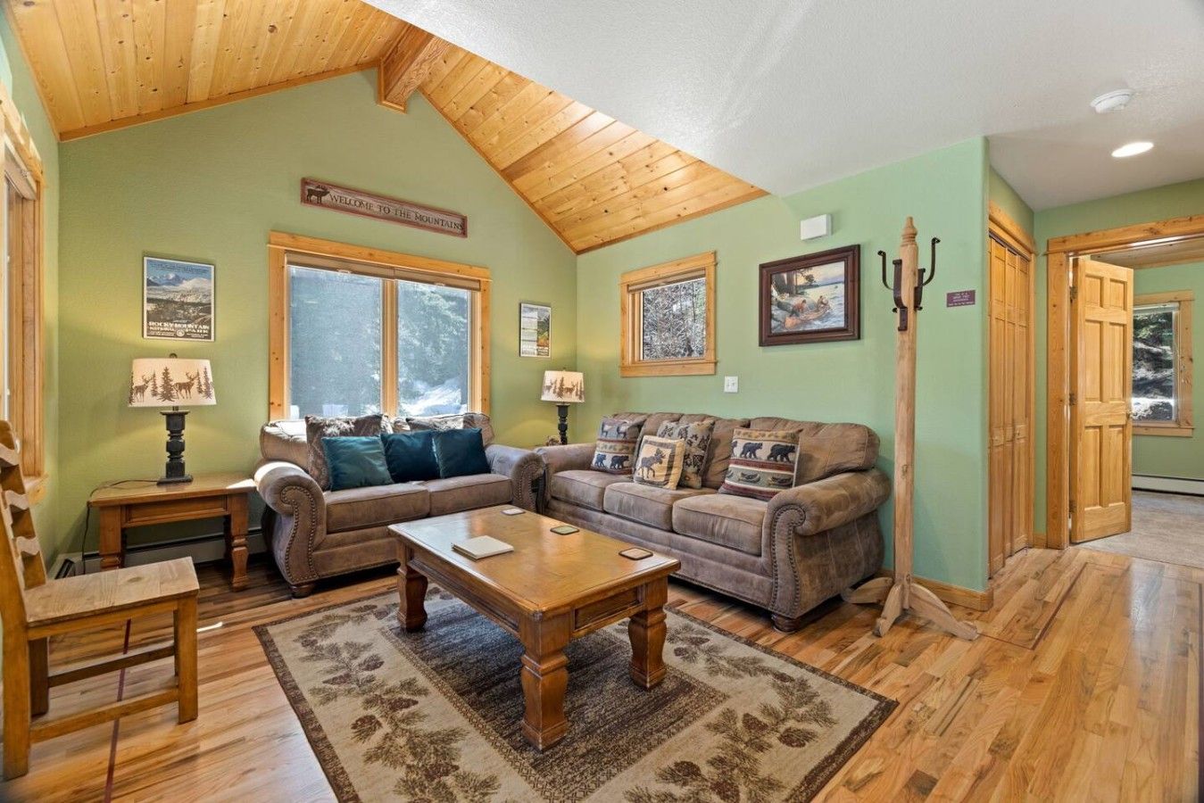 A cozy living room with a high ceiling, a fireplace, and a view of the mountains.