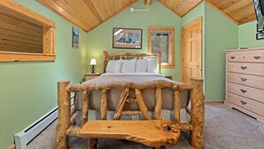 Une chambre à coucher avec un lit en bois au style rustique, une table de chevet, une commode et un ventilateur de plafond.