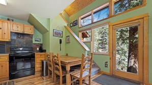 Une cuisine avec des meubles de rangement en bois, une cuisinière et une table à manger avec des chaises.