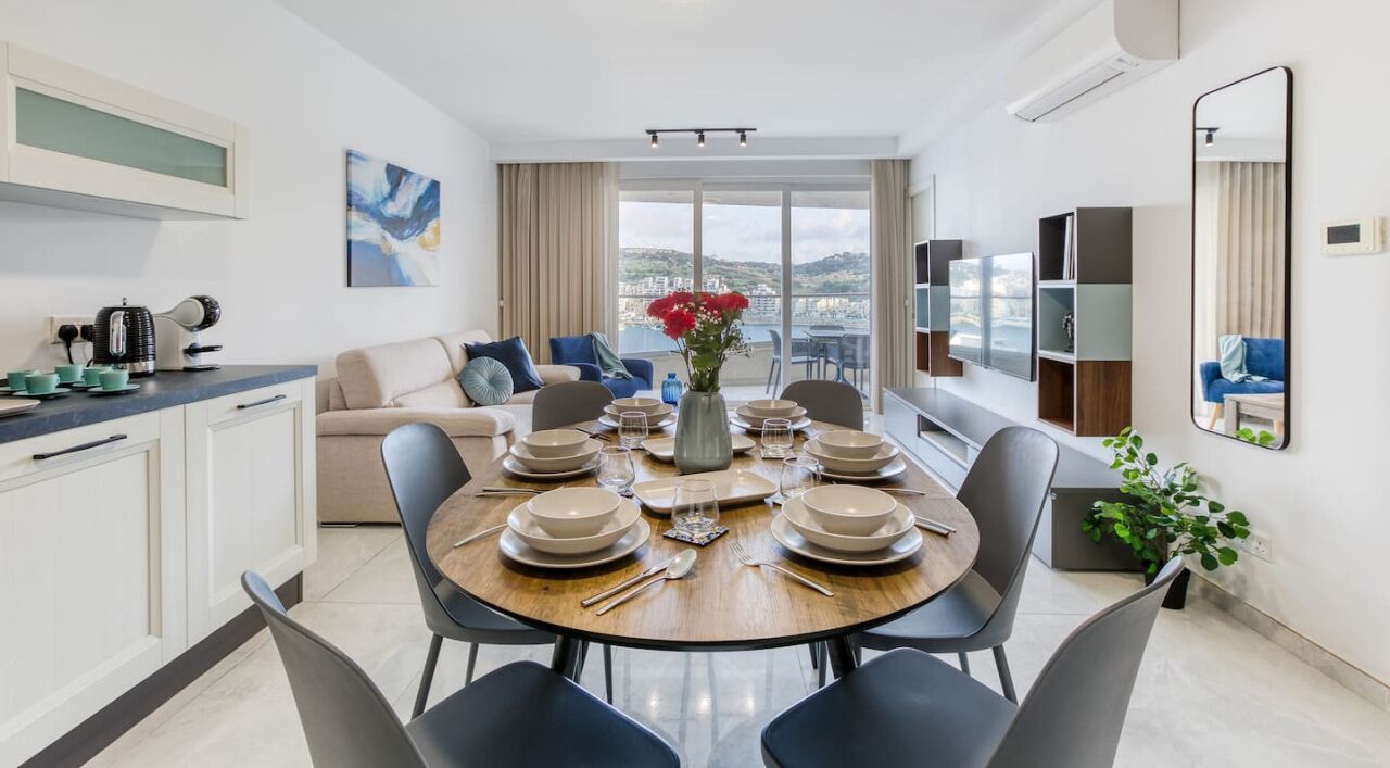 Un comedor moderno con una mesa redonda para seis personas, un sofá y vistas a la ciudad.
