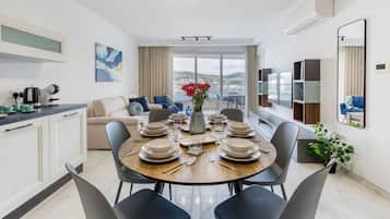 Un comedor moderno con una mesa redonda para seis personas, un sofá y vistas a la ciudad.
