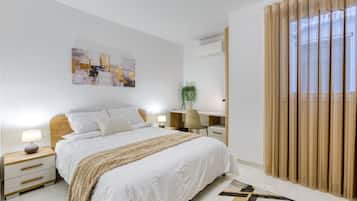 Un dormitorio moderno con una cama grande, mesitas de noche, un escritorio y una ventana con cortinas.
