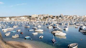 Una marina llena de barcos, una playa de arena y un paisaje urbano al fondo.