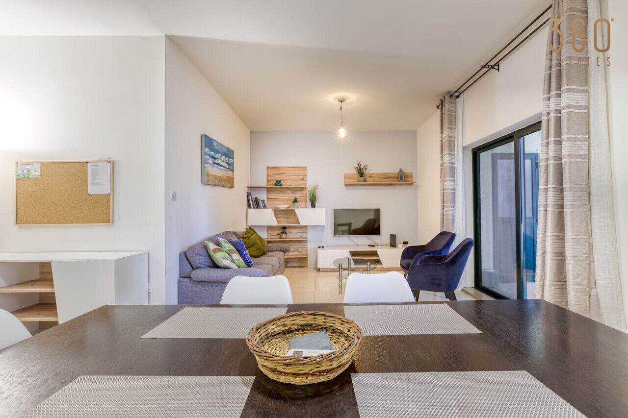 Una sala de estar moderna con un sofá, sillas, un televisor y un comedor con mesa y sillas.