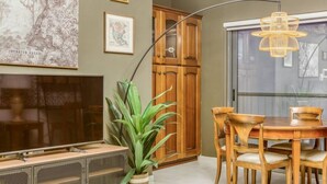 A dining area with a wooden table and chairs, a television, and a plant. - Stylish & Cosy 1BR APT in the Heart of Paceville (St. Julian`s)
