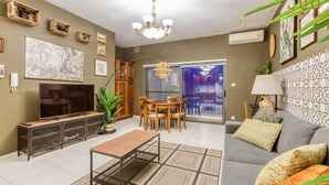 A living room with a TV, sofa, coffee table, and dining area. - Stylish & Cosy 1BR APT in the Heart of Paceville (St. Julian`s)