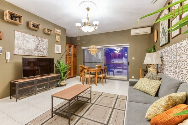 A living room with a TV, sofa, coffee table, and dining area.