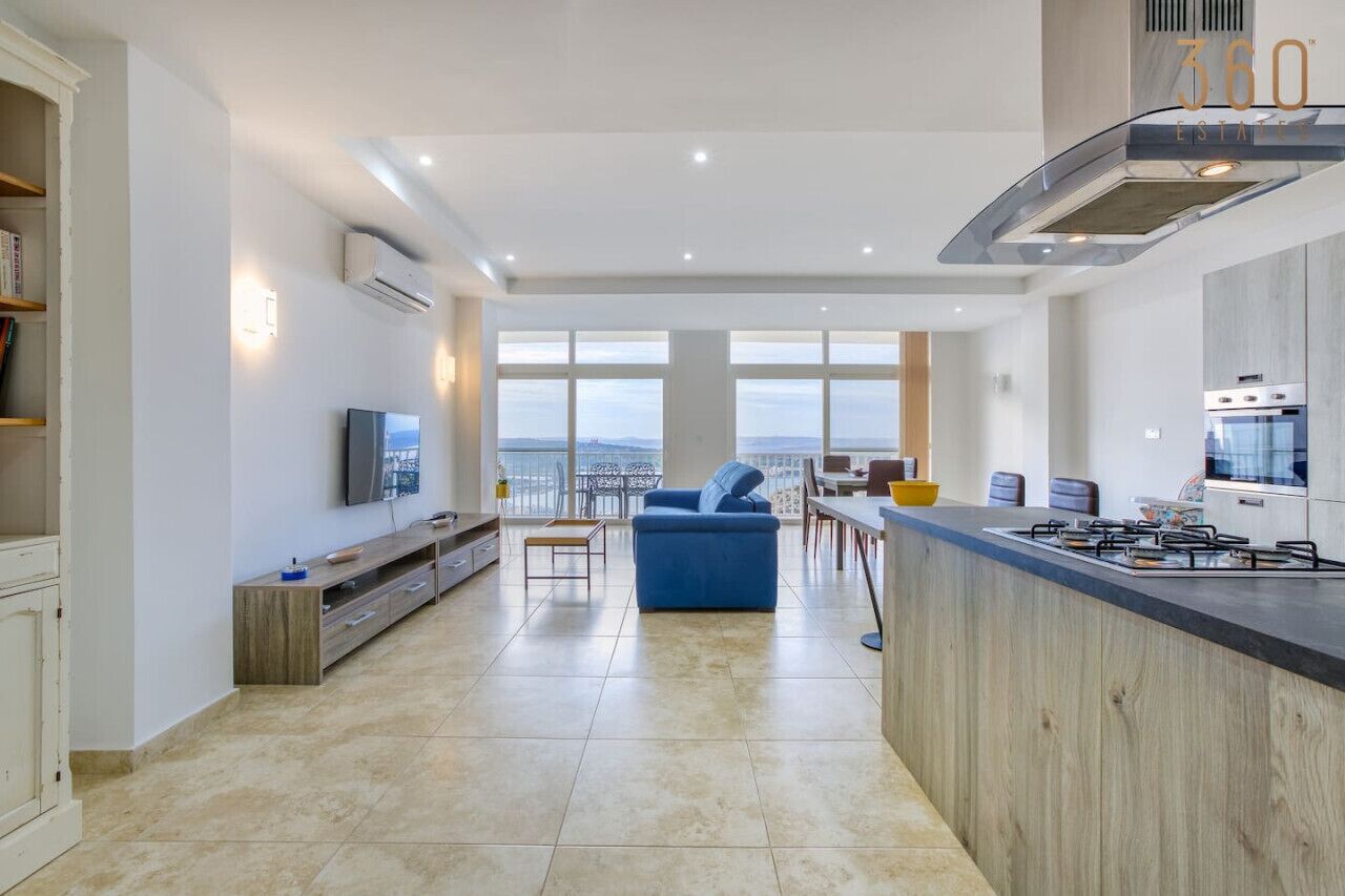 Una cucina moderna con una grande isola, un'area pranzo con vista e un soggiorno con divano e TV.