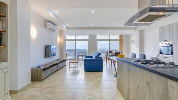 Una cucina moderna con una grande isola, un'area pranzo con vista e un soggiorno con divano e TV.