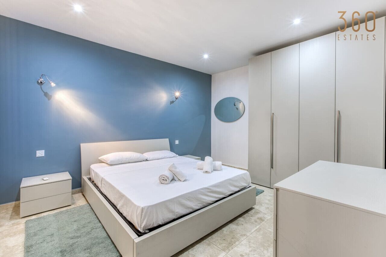 Una camera da letto con un letto, comodini, un armadio e uno specchio appeso al muro.
