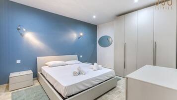 Una camera da letto con un letto, comodini, un armadio e uno specchio appeso al muro.