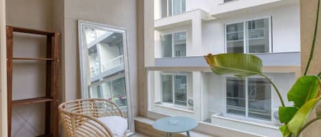 A balcony with wicker chairs, a small table, and a potted plant.