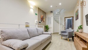 Un intérieur moderne avec un canapé, un fauteuil, une console en bois et un escalier en colimaçon.