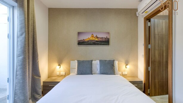 Une chambre d’hôtel avec un grand lit, deux lampes de chevet, un tableau au mur et une porte en bois.