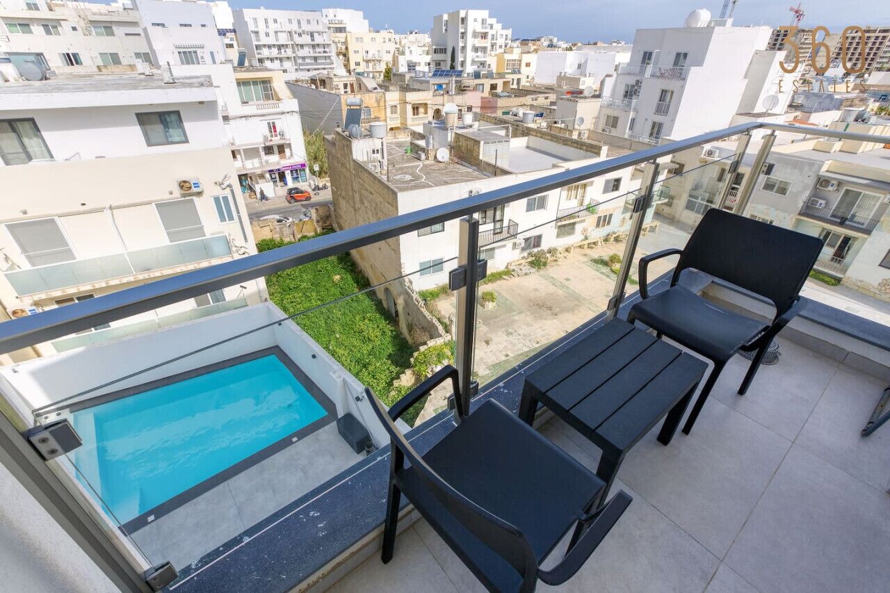Un balcón con piscina, dos sillas y vista a una zona residencial.