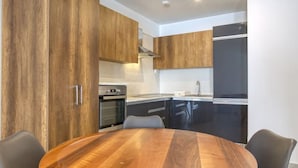 A modern kitchen with wooden cabinets, a round wooden table, and black chairs.