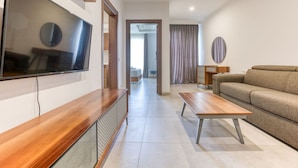 A modern living room with a flat-screen TV, a wooden coffee table, and a beige sofa.