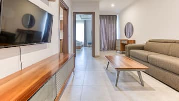 Una sala de estar moderna con un televisor de pantalla plana, una mesa de centro de madera y un sofá color beige.