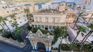 Un bâtiment historique doté d’une arche imposante, entouré de palmiers et de bâtiments modernes.