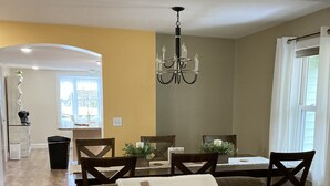 A living room with a brown sofa, patterned cushions, a chandelier, and a dining area with a table and chairs. - Leaping Waters - peaceful home located along the West Canada in Barneveld, NY.   (Barneveld)